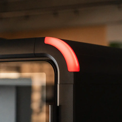 Close-up of a black computer case corner with a glowing red LED light in a blurred indoor setting.