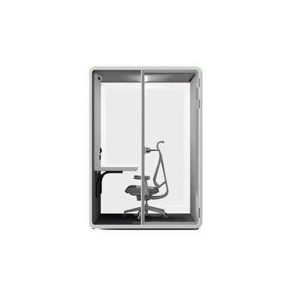 A modern glass privacy booth with a gray frame, featuring a built-in desk on the left side and a gray office chair inside, shown against a plain white background.